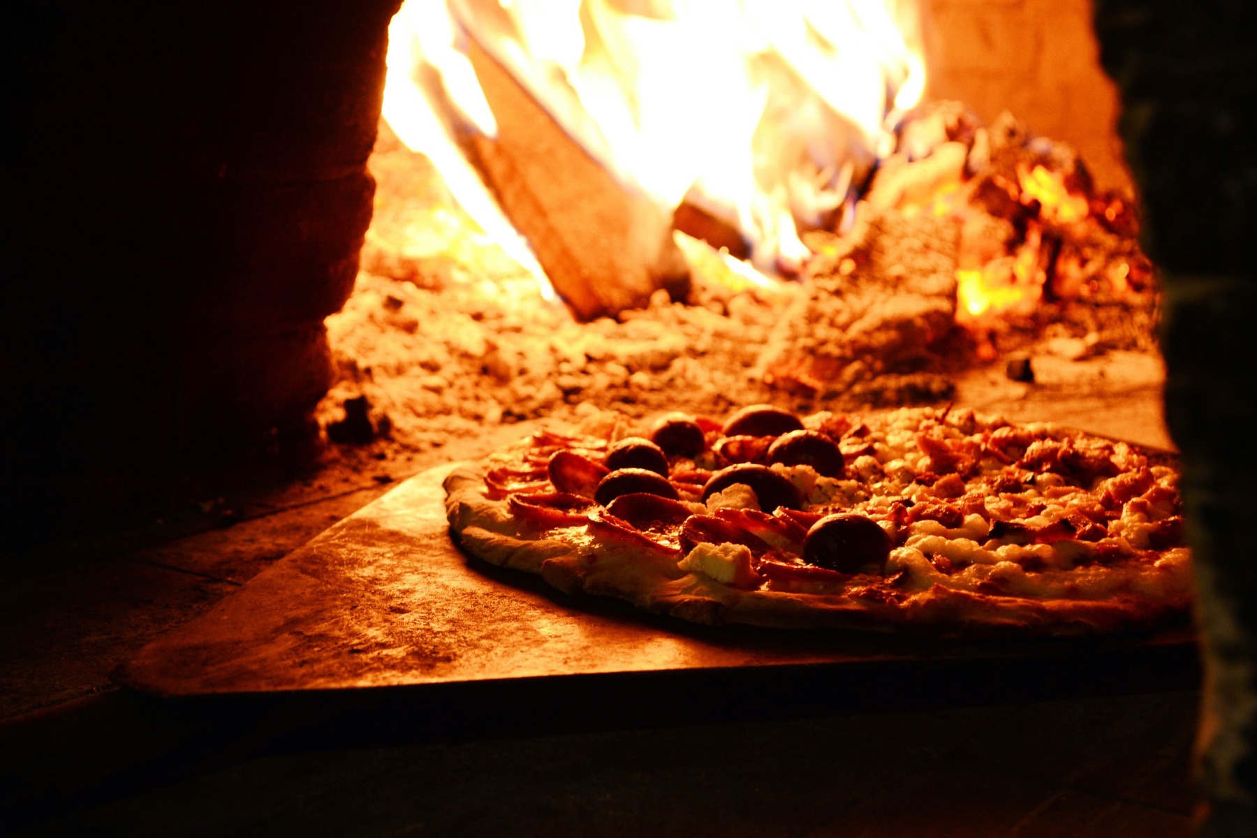 cooking pizza in wood fired pizza oven
